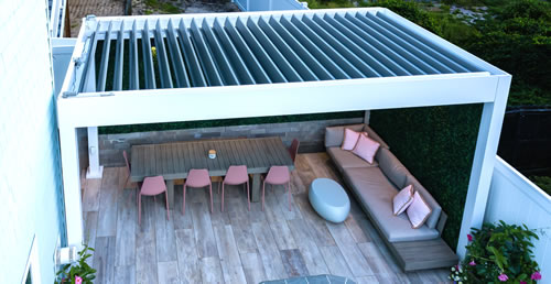 white pergola on a deck with louverred roof