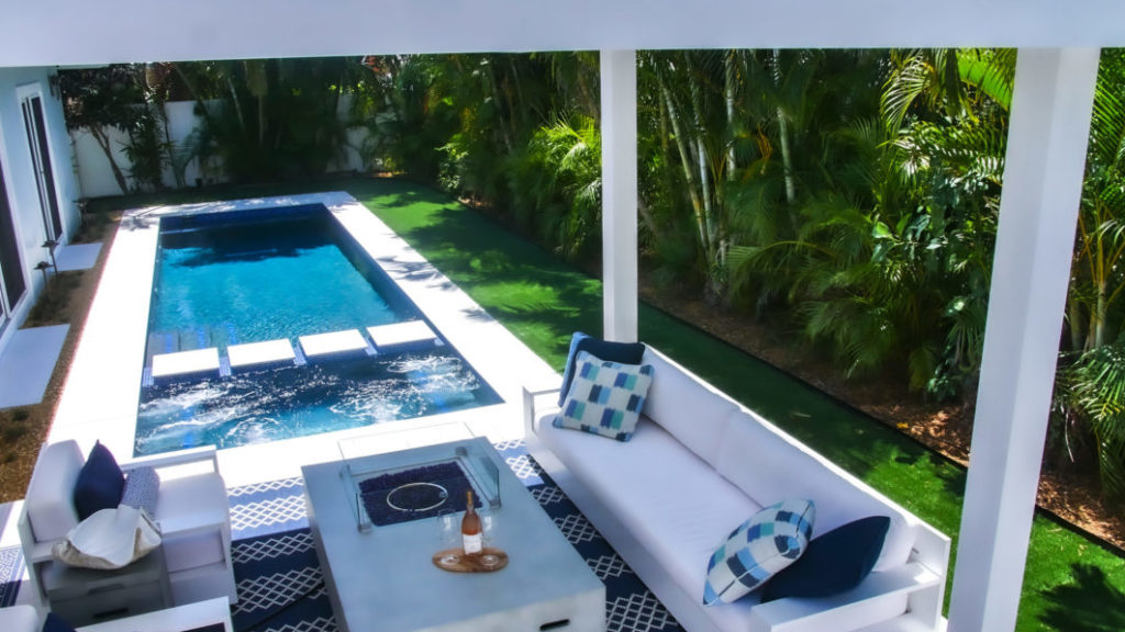 Outdoor table with gas powered fire pit beneath pergola