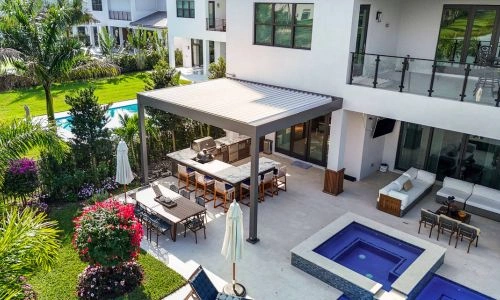 Drone view - Residential black and white wall-mounted shade structure with outdoor kitchen - R-BLADE pergola by Azenco Outdoor