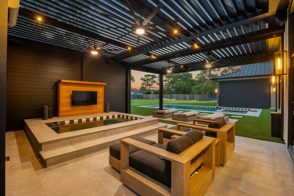 black r-blade pergola attached to house in backyard with fans lights and firepit