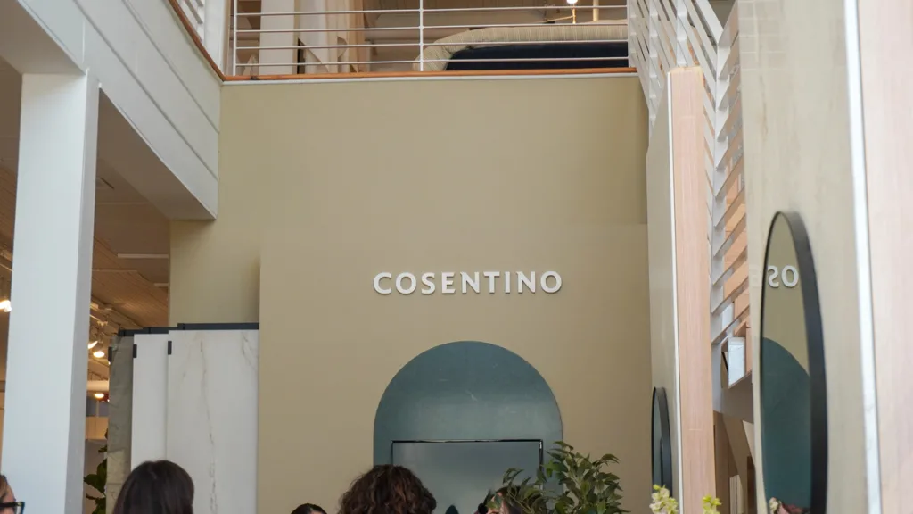 Interior view of the Broad Hall space, showcasing the 'Cosentino' brand sign above an arched entryway, with modern architecture and a mezzanine level visible. This is one of the partner exhibition areas located near the Azenco R-Blade installation at High Point.