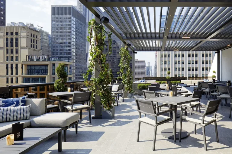 Gray and bronze R-BLADE™ louvered pergola with LED lights on a city rooftop restaurant terrace