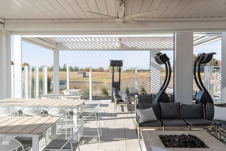 White R-BLADE™ motorized louvered pergola with screens, LED lights and a fire pit on a commercial terrace