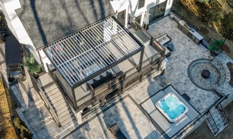 Aerial view of a dark gray R-BLADE™ louvered pergola over a backyard deck next to a hot tub
