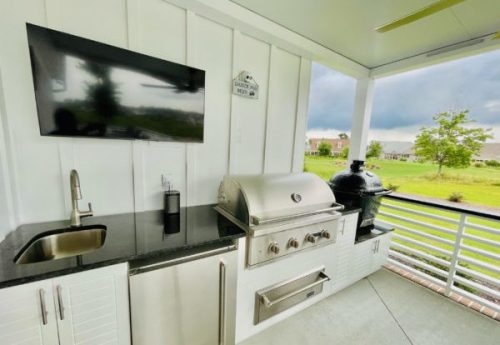 covered outdoor kitchen with grill, oven and charcoal smoker