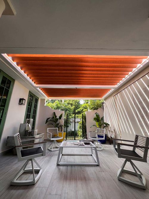 Outdoor room covered with R-BLADE motorized louvered roof system in wood grain finish - Azenco